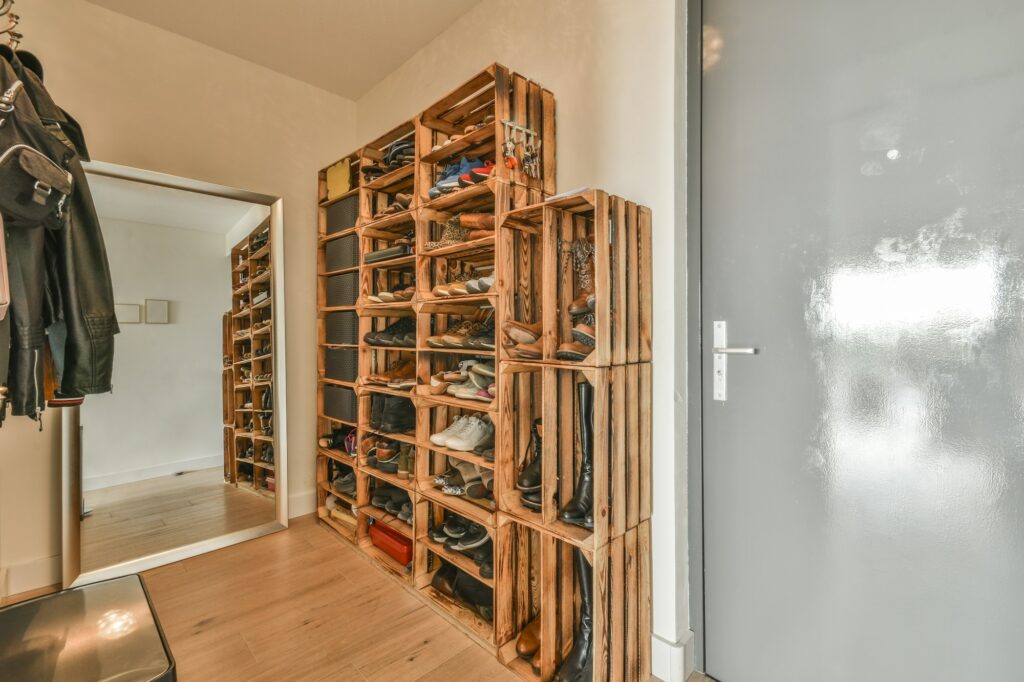 Narrow corridor with shoe rack near doors, white walls and wooden floor